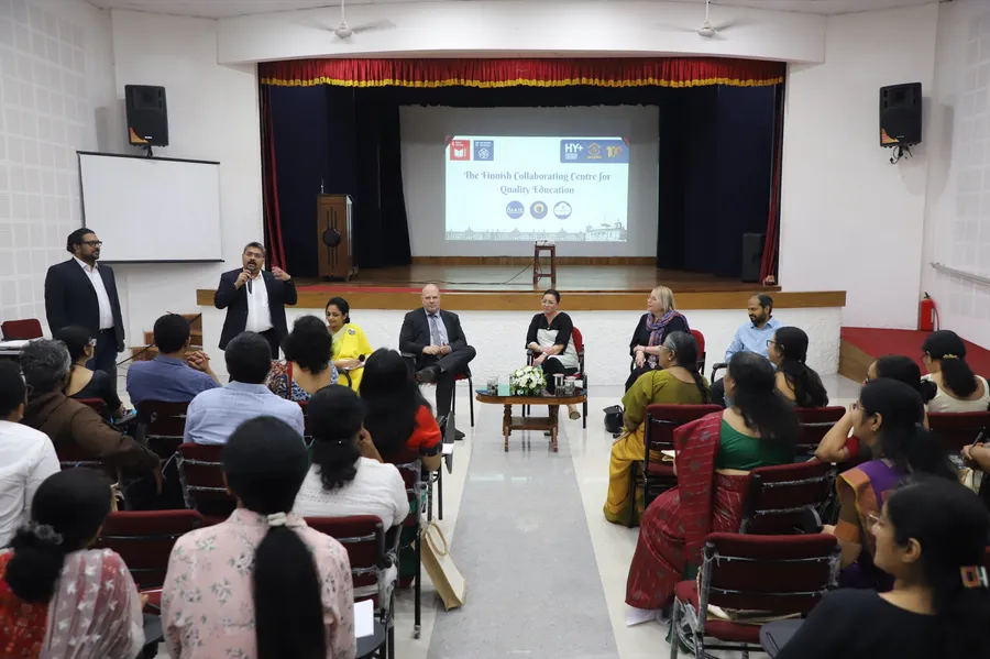 A panel of Finnish and Indian educators in front of a screen reading The Finnish Collaborating Centre for Quality Education, with an audience of teachers.